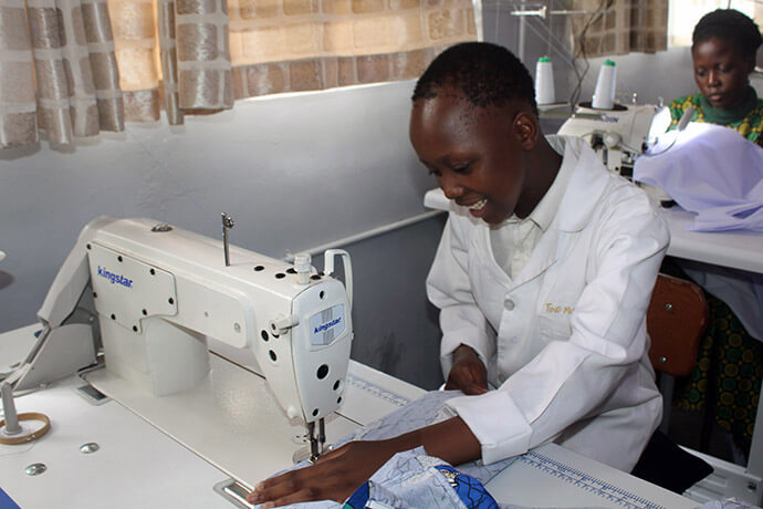 Shupikai Madeyi, a 15-year-old student at Murewa High School in Murewa, Zimbabwe, smiles joyfully while operating a straight-line stitching machine. Madeyi shared how passionate she is about using the machines in the factory department. Photo by Kudzai Chingwe, UM News.