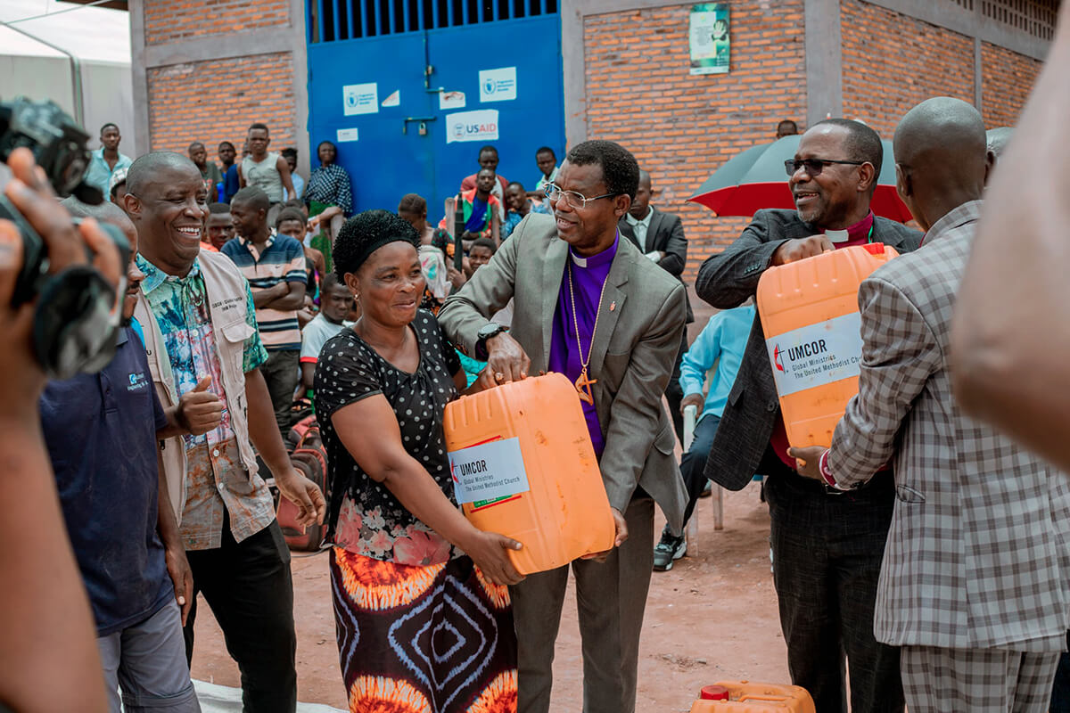 Bishop João Sambo of Mozambique (right) and Bishop Emmanuel Sinzohagera of Burundi (center) distribute cans of vegetable oil at the Musenyi camp in Burundi. The bishops were among a United Methodist delegation who visited the camp in March to offer physical and spiritual support to refugees fleeing conflict in eastern Congo. Global Missionary Abro Patrick stands to the left. Photo courtesy of the communications department of the Burundi-Rwanda Episcopal Area.