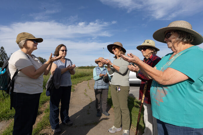 Sacred Ground field trip participants raise their hands in praise following a hike on the Laguna de Santa Rosa trail near Sebastopol, Calif. Participants in a Sacred Ground field trip hike through grassland on the Laguna de Santa Rosa trail near Sebastopol, Calif. Photo by Mike DuBose, UM News.