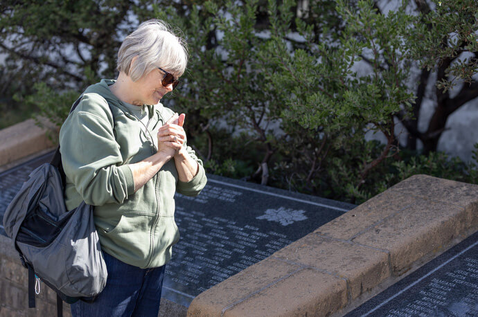 The Rev. Laurie Bayen prays at a memorial honoring some 890 Indigenous people, members of the Coast Miwok, Patwin, Wappo and Pomo tribes, who died at the Mission between 1824 and 1839. Bayen was leading a field trip for the Sacred Ground project, which she developed. Photo by Mike DuBose, UM News.