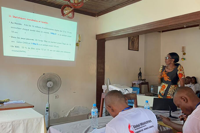 La Dr Yvette Neema, médecin spécialiste en gynécologie aux Cliniques universitaires de Kisangani, présente des statistiques sur les grossesses précoces devant une assemblée de jeunes méthodistes attentifs. Elle intervient dans le cadre d'un séminaire biblique sur le leadership à Kisangani visant à transformer 50 jeunes leaders en agents de santé, de développement et de paix pour leurs communautés. Photo by Judith Osongo Yanga, UM News.