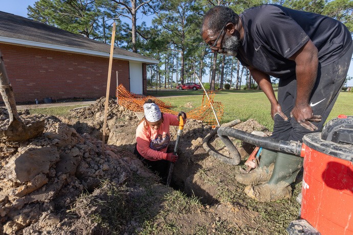 Crystal Latham makes a final check for leaks after replacing a water pipe at an apartment complex in Gulfport, Miss. Latham, a graduate of the Women in Construction program in Biloxi, Miss., owns her own plumbing and remodeling business. Watching from above is her employee, Richard Macklin.