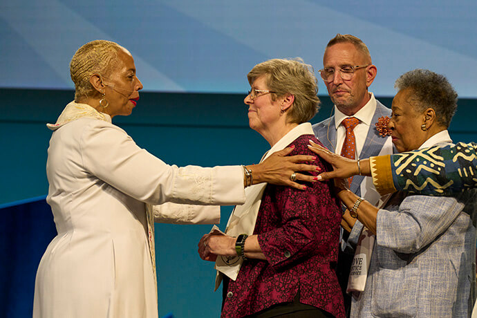 Bishop Tracy S. Malone congratulates Elizabeth Kroll after her consecration as a deaconess on May 15 at the United Women in Faith Assembly in Indianapolis. Also laying on hands are Scott James-Vickery and Clara Ester. Photo by Paul Jeffrey, United Women in Faith.
