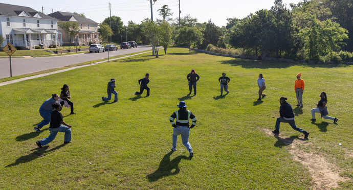 Students and instructors in the Women in Construction program begin their day with stretching and balance exercises at a neighborhood playground in Biloxi. 