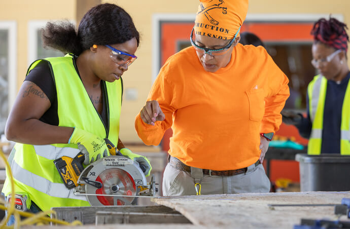 Quasha Johnson learns to use a circular saw under the watchful eye of instructor Iris Torres-Soto at the Women in Construction program. 