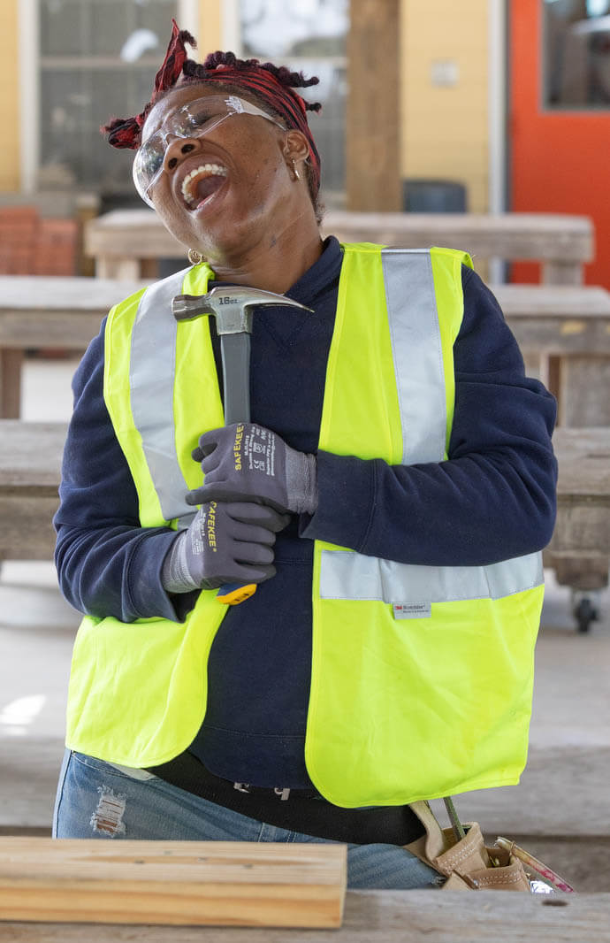 Kenisha Thomas sings into her hammer during a break at the Women in Construction training program. The students took part in a “Whitney Houston Drum Challenge,” where participants try to time a drum beat to Houston’s 1992 hit “I Will Always Love You.” 