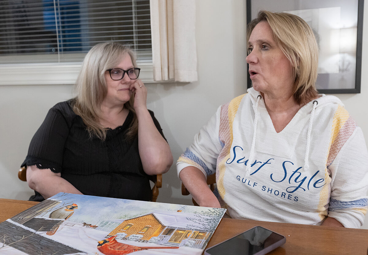 Jennifer Ivey (left) and Carolyn Weaver relax together at the Family Reconciliation Guest House in Nashville, Tenn. The ministry provides a comfortable, safe and free place for friends and families of inmates to stay while visiting loved ones who are incarcerated. The painting on the table was created by Gary Wayne Sutton, a death row inmate whom Weaver visits regularly. Photo by Mike DuBose, UM News.