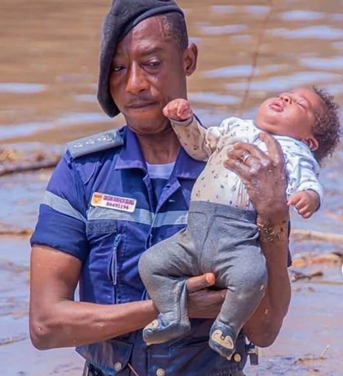 Oficial do Serviço de Protecção Civil e Bombeiros de Angola resgatando uma criança durante as cheias no Rio Cavaco em Benguela. Mais de 1.600 pessoas foram resgatadas com o apoio da Força Aérea, Marinha de Guerra e dos Bombeiros. A criança resgatada recebeu assistência médica no Hospital Geral de Benguela. Foto cortesia da Administração de Benguela, Angola. Notícias MU. 