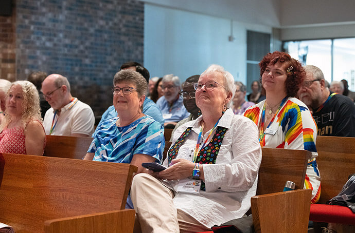 Jan Lawrence (in white) sits next to her wife, Lindi Lewis, during a presentation at the 2025 Reconciling Ministries Network convocation. The gathering celebrated the removal of denomination-wide restrictions targeting LGBTQ people. Lawrence said, “Every reconciling United Methodist and every reconciling United Methodist ministry played a role in getting to this moment.” File photo by Joscie Cutchens, UM News.