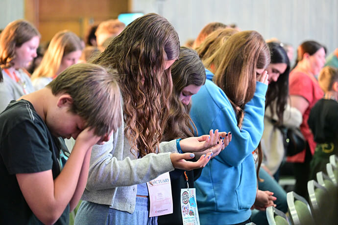 Participants bow their heads during morning worship at the Global Young People’s Convocation. Each day began with worship and concluded with an invitation to the communion table, reinforcing the concepts of unity and consecration as fundamental pillars of the ministerial work carried out internationally by The United Methodist Church. Photo by the Rev. M. Scott Hughes, Discipleship Ministries.