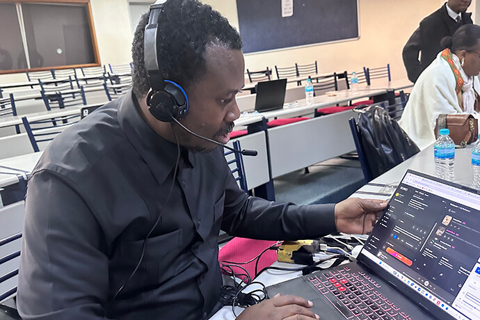 The Rev. Fiston Lutuku Okito, director of communications for the Central Congo Episcopal Area, uses a laptop and headphones to compose a song using an artificial intelligence platform. The hands-on activity took place as part of a course on artificial intelligence and digital information management offered as part of the new strategic communications program in Mutare, Zimbabwe. Photo by Chadrack Tambwe Londe, UM News.