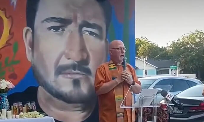 The Rev. Eric Folkerth, lead pastor of Kessler Park United Methodist Church in Dallas, speaks at a prayer vigil June 10 to grieve the death of Lorenzo Salgado Araujo, who was fatally shot by an ICE agent who had followed his truck in an unmarked vehicle. Folkerth stands in front of a mural in Dallas’s Oak Cliff neighborhood that depicts Norlan Guzmán-Fuentes, one of two detainees killed by a shooter targeting the Immigration and Customs Enforcement facility. Photo courtesy of Folkerth.