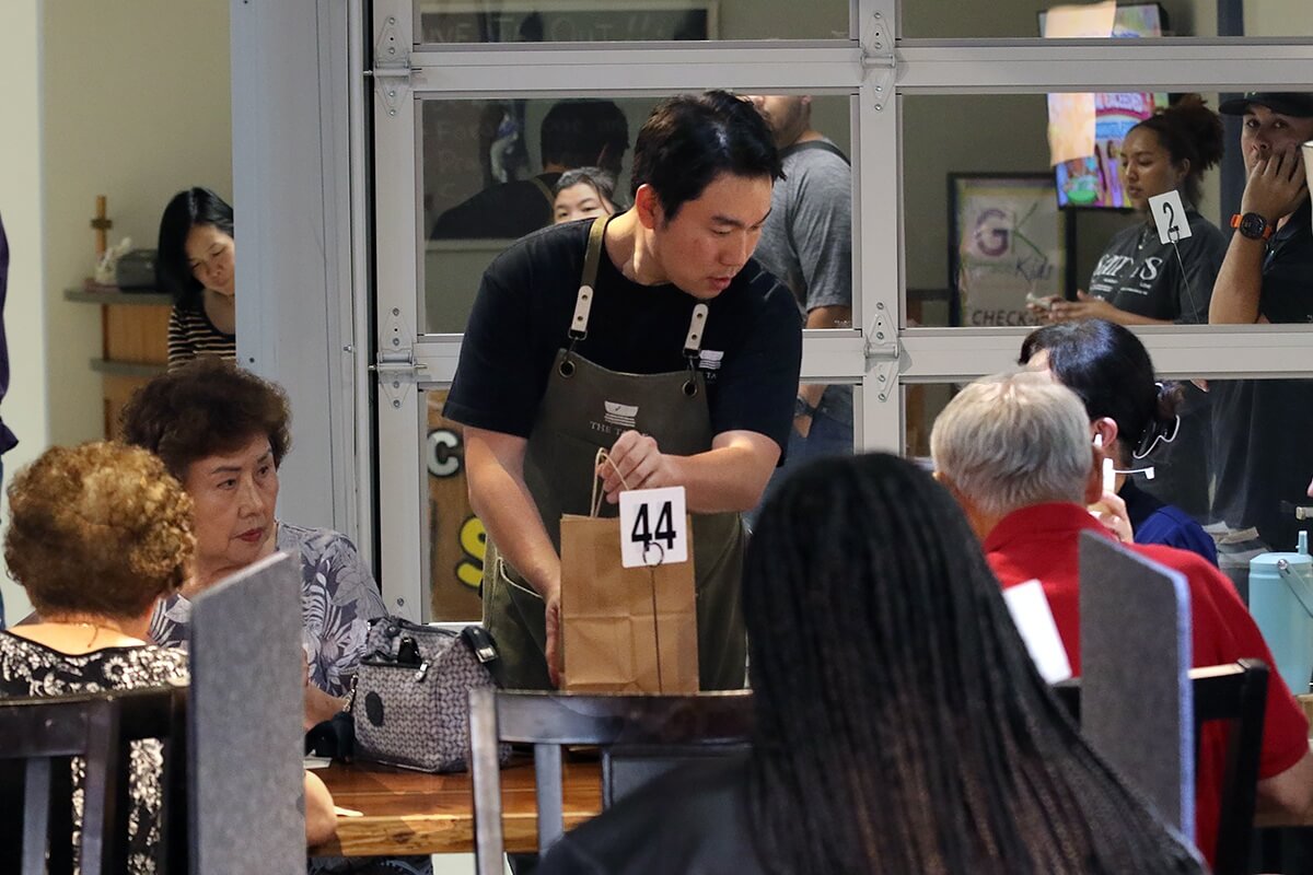 모닥불연합감리교회는 한식당 ‘더 테이블(The Table Korean Cuisine)’을 통해 음식과 환대로 교회 담장 너머의 사람들과 관계를 맺고 있다. 모닥불 연합감리교회 담임이자  ‘더 테이블’ 셰프인 김창현 목사가 포장 주문한 음식을 손님에게 건네며 이야기를 나누고 있다. 뒤편에는 자리가 나기를 기다리는 손님들이 보인다. 사진, 김응선(Thomas E. Kim) 목사, 연합감리교뉴스.