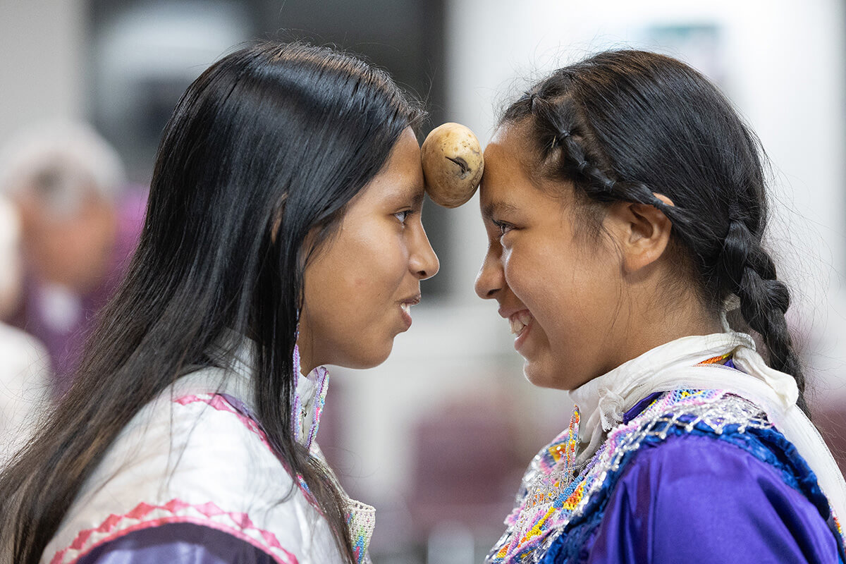 Sisters Daniele (left) and Danica Bell take part in the potato dance, where pairs of dancers with hands held behind their backs hold a potato between their foreheads and try to dance to the beat of a drum without letting the potato fall. The dance, part of the Native Moccasins Rock gathering in Bon Aqua, Tenn., was sponsored by Native American Ministries of the Tennessee-Western Kentucky Conference of The United Methodist Church. Photo by Mike DuBose, UM News. 