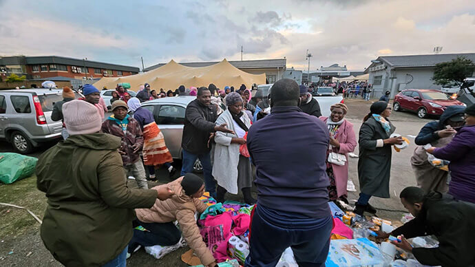United Methodists from Bishop Abel Tendekayi Muzorewa, Hebron and Bethel Circuit in the South Africa Conference’s Cape Coastal District distribute clothes, food and sanitary towels to migrants from Malawi, Zimbabwe and Angola at the Department of Home Affairs Repatriation Center in Epping, Cape Town. Photo by Alvin Makunike, UM News.