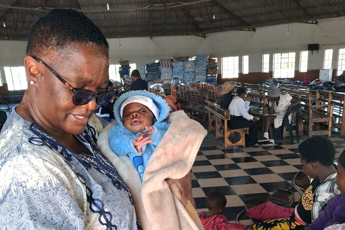 The Rev. Heather J. Zisengwe, superintendent for The United Methodist Church’s Bulawayo Midlands District in Zimbabwe, holds a baby at a transit camp set up by the Zimbabwe Council of Churches for migrants who have left South Africa amid anti-immigration protests. The temporary center in the sanctuary of the United Church of Christ in Southern Africa in Njube was the hub for humanitarian efforts by mainline churches in Zimbabwe. Photo courtesy of the Rev. Heather J. Zisengwe.