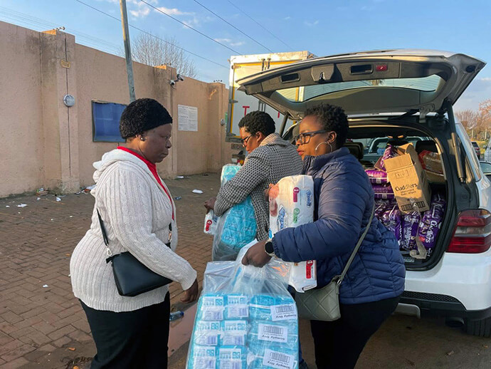 Members of United Women in Faith in the South Africa Conference’s Central District unload supplies to donate and distribute to immigrants being processed at the Zimbabwe Consulate in Johannesburg, South Africa, where they are waiting for buses to repatriate them to their country of origin. The migrants fled to the consulate for safety following nationwide protests. Photo by Alvin Makunike, UM News.
