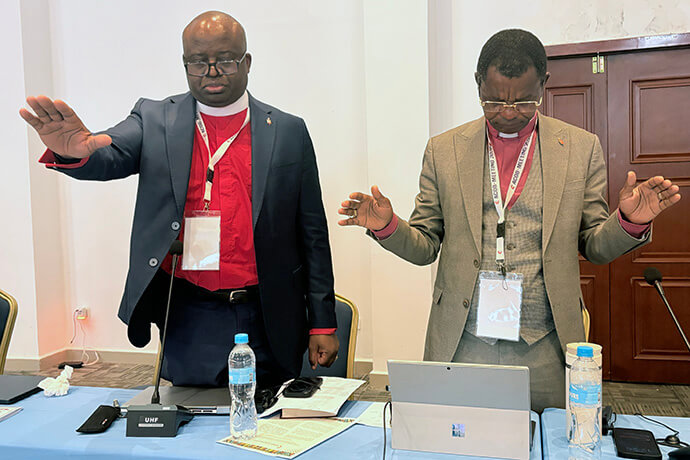 Bishop Mande Muyombo, president of the Africa College of Bishops, and Bishop Emmanuel Sinzohagera stretch out their hands in prayer for outgoing Liberia Minister of Justice N. Oswald Tweh who served as president of The United Methodist Church’s Judicial Council from 2016 to 2024. Photo by Eveline Chikwanah, UM News.
