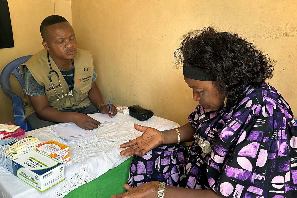 Dr. Gustave Ngoy, head of the non-malaria program for the Tanganyika Episcopal Area’s medical coordination team, speaks with Cathérine Shabani during a consultation at a mobile clinic in Kalemie, Congo. The 60-year-old mother of 11 children and a member of Jerusalem (United Methodist) Church received a free health checkup as part of a medical initiative funded by Bishop Nelson Kalombo Ngoy to benefit annual conference delegates and vulnerable populations. Photo by Chadrack Tambwe Londe, UM News.