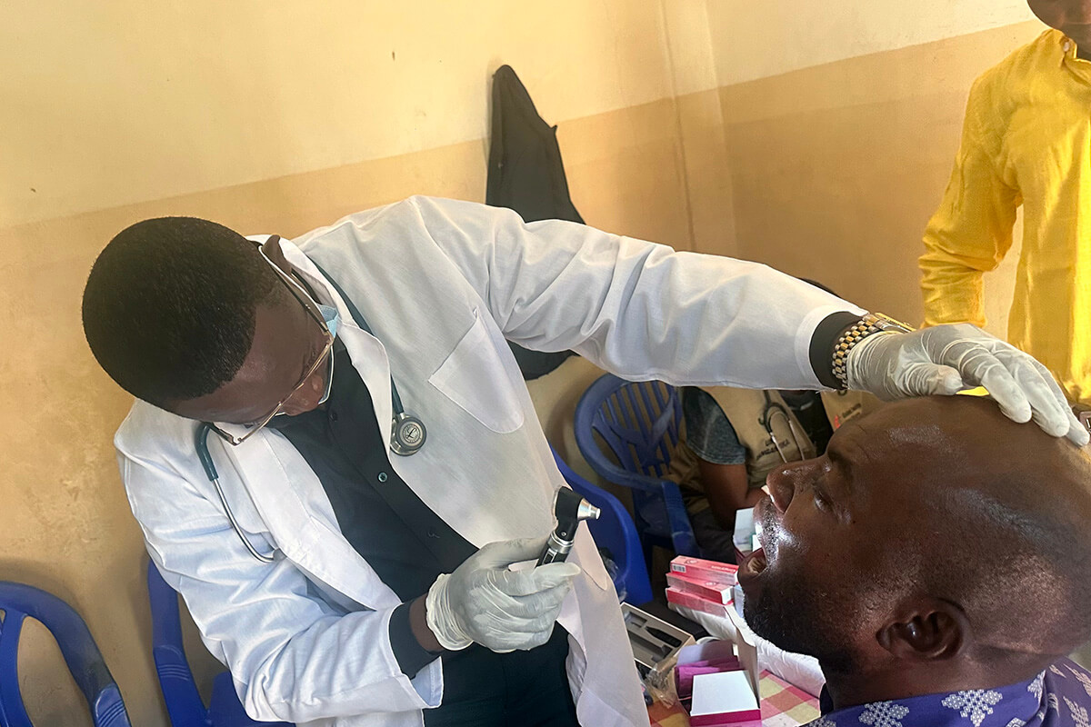 Dr Élisée Kilumba, coordinateur des ministères médicaux de la région épiscopale du Tanganyika, examine la gorge d’un patient lors d’une consultation à Kalemie, au Congo. Plus de 600 membres et responsables d’Églises de Manono et de Kalemie ont été soignés lors des conférences annuelles de l’Église Méthodiste Unie dans le sud-est du pays. Photo de Chadrack Tambwe Londe, UM News.
