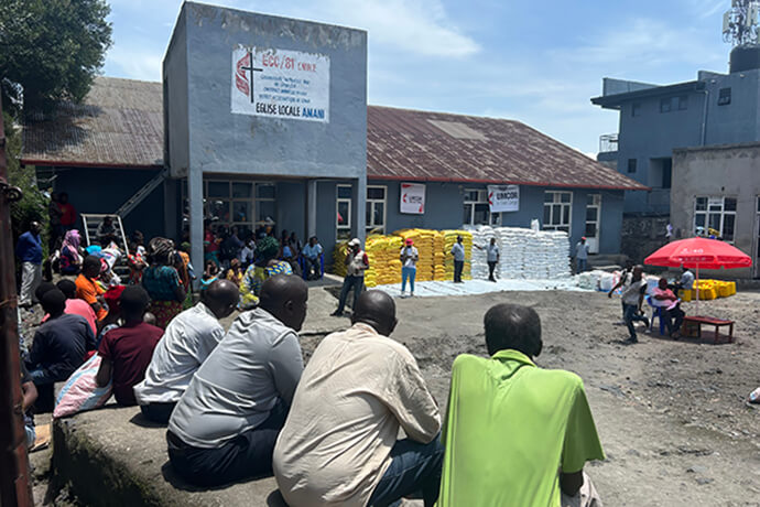 Des bénéficiaires et des membres de l’Église se rassemblent devant l’église locale d’Amani à Goma, au Congo, avant le début d’une distribution mensuelle de vivres organisée par le Bureau de gestion des catastrophes du Comité Méthodiste Uni de secours (UMCOR) dans la Région épiscopale de l’Est du Congo. Cette initiative vise à rendre dignité et stabilité aux familles déplacées et fragilisées par l’insécurité et la hausse du coût de la vie dans la région. Photo : Jolie Shabani Mulebinge, UM News.