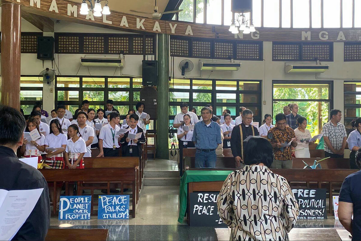 Mervin Toquero, (center in blue polo shirt), a United Methodist and leader of the National Council of Churches in the Philippines, joins with other ecumenical church leaders, peace advocates and others at the 2026 Day of Prayer for Just Peace that took place in Quezon City. Those gathered raised concerns over the social and environmental risks of the U.S.-led Pax Silica initiative. Photo by Donna Mae Delfin, National Council of Churches in the Philippines.