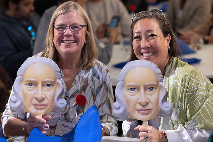 Patricia Luna (left) and Allison Mark display fans with a likeness of Methodism founder John Wesley during the United Methodist Leadership Gathering at Knox United Church in Calgary, Canada. Photo by Mike DuBose, UM News.
