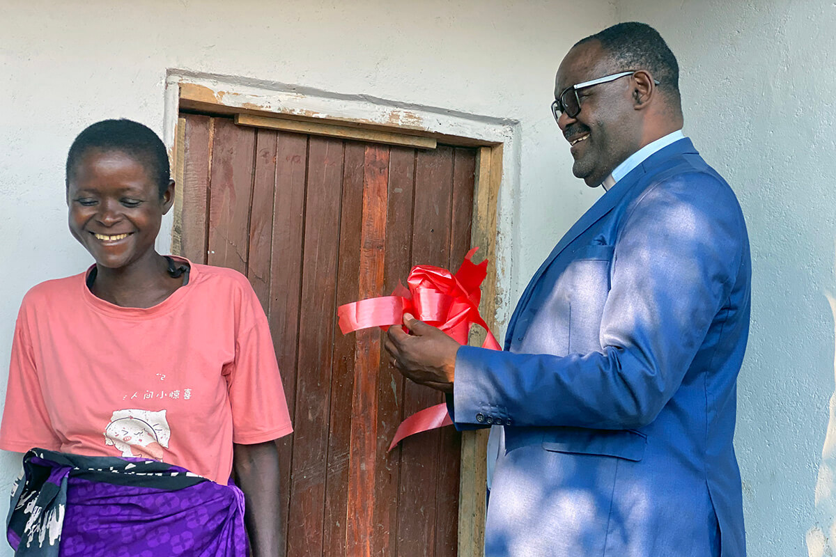 The Rev. Godfrey Gaga (right,) Malawi Provisional Conference superintendent, removes the ribbon from the door of Annie Katumbi’s new home in Ngabu Village in Chikwawa, Malawi. The house was built as part of the United Methodist Committee on Relief’s Phase 2 recovery efforts after Cyclone Freddy devastated the area in 2023. Photo by Francis Nkhoma, UM News.